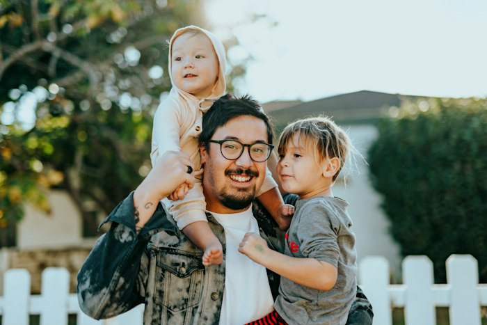 A father outdoors with two small children